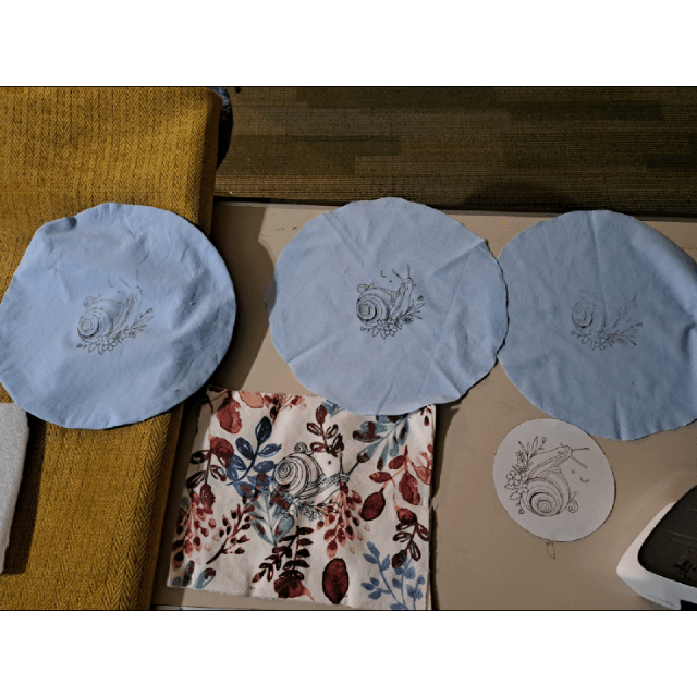 A gif showing the process of embroidering a snail on a pillow.